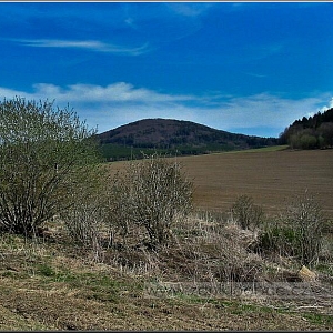 Pohled na lokalitu samot (v pozadí Jezvinec - 739m) nacházejících se na návrší uprostřed polí, k nimž všechny cesty byly přeorány.