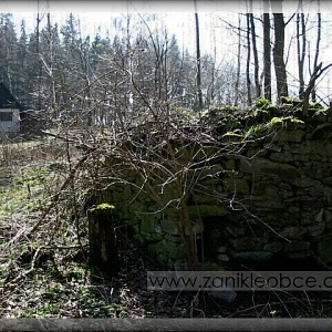Výrazné ruiny po předešlém stavení z jiného úhlu, v pozadí novodobá chata na starých základech.