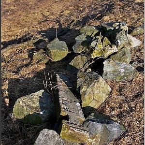 Torzo křížku a rozorané kamenné základy po usedlosti.