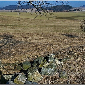 Pohled od rozoraných kamenných základů a soklu křížku u samoty (475 m n. m.), v pozadí na Tanaberk s kostelem Sv. Anny.